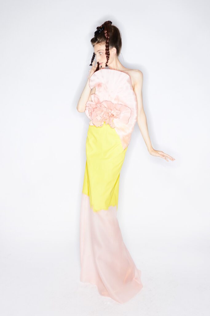 A fitted sleeveless silk dress featuring a high-neck and tiered design in pink and yellow.