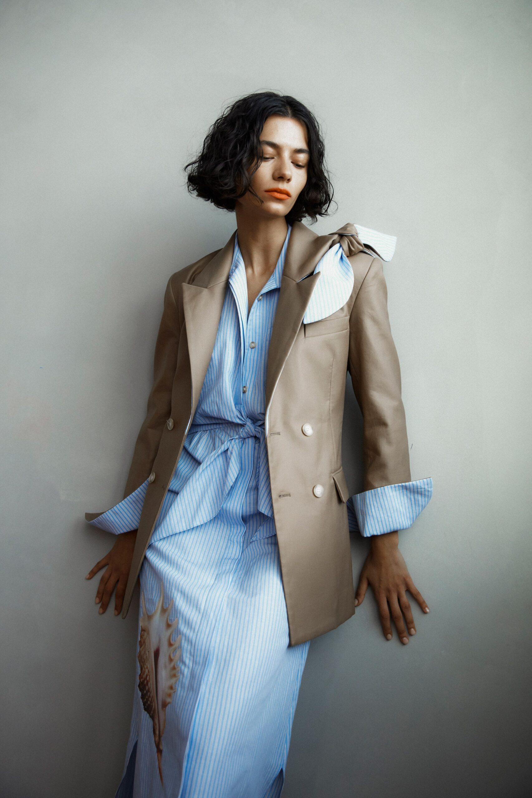 A relaxed beige blazer paired with a collared striped dress featuring button details.