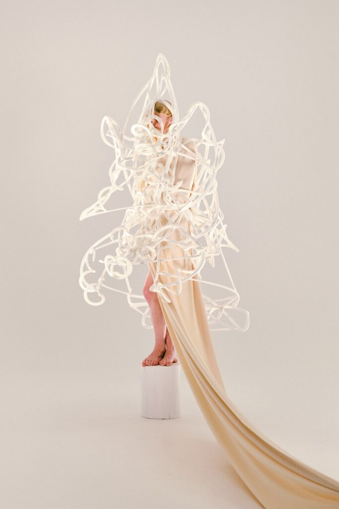 A draped beige silk dress with an asymmetric design and a flowing silhouette.