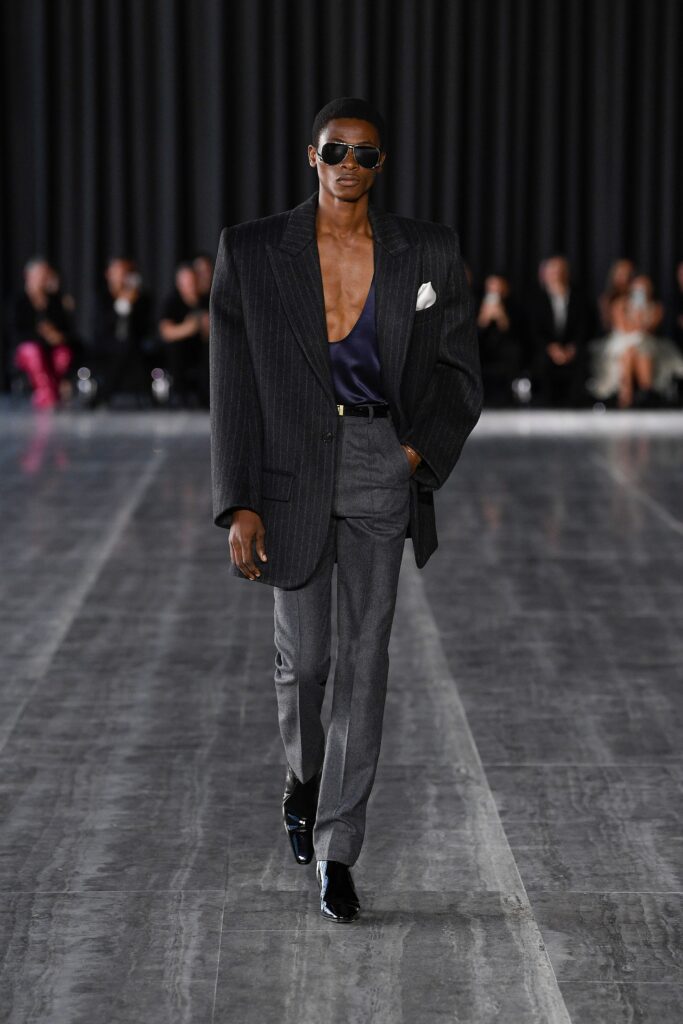 A tailored black and gray suit with a long-sleeve jacket and structured design details.