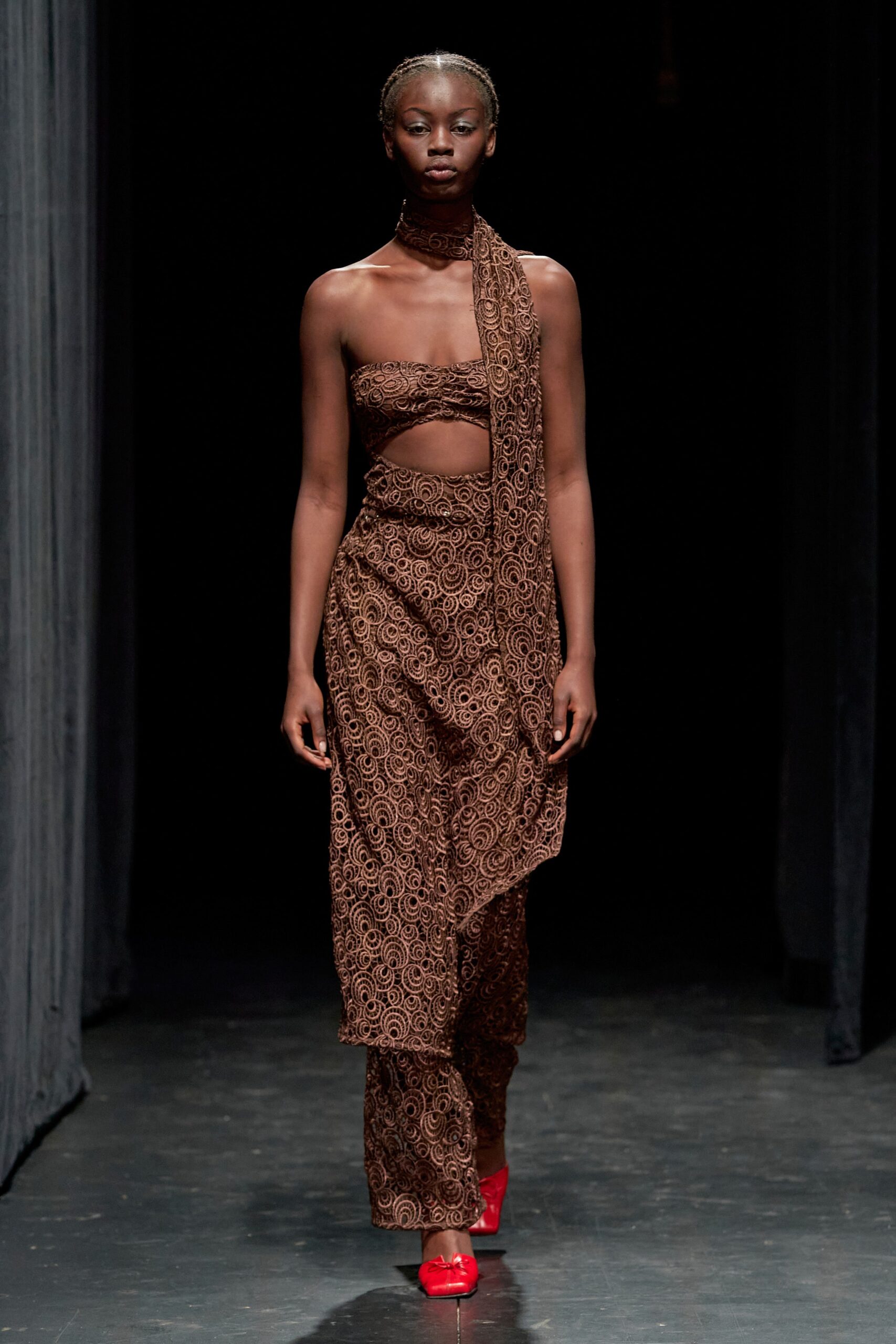 A fitted brown silk dress with a sleeveless cutout design and asymmetric detailing.
