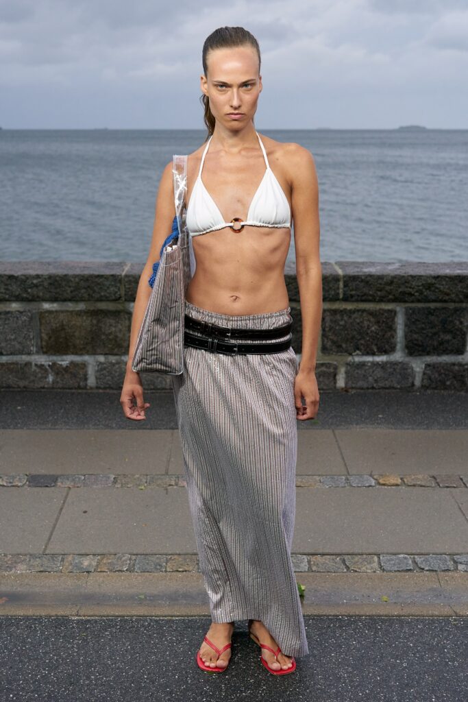 A fitted white bikini paired with a high-waisted striped skirt for a chic beach look.