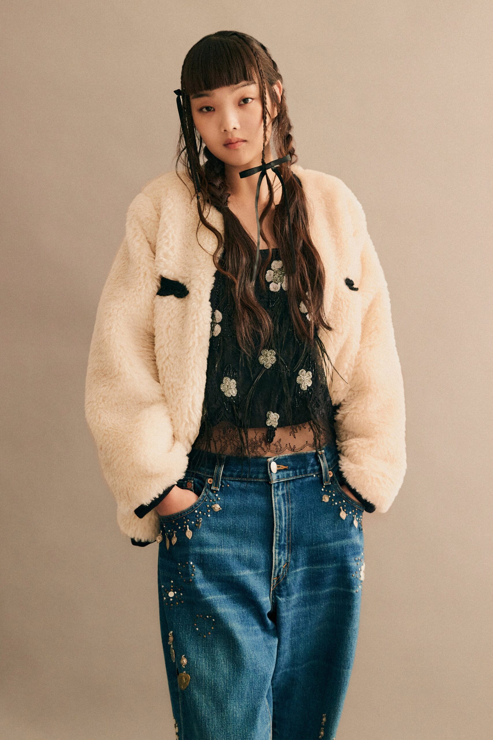 A relaxed beige faux-fur jacket paired with blue denim pants, featuring a buttoned design.