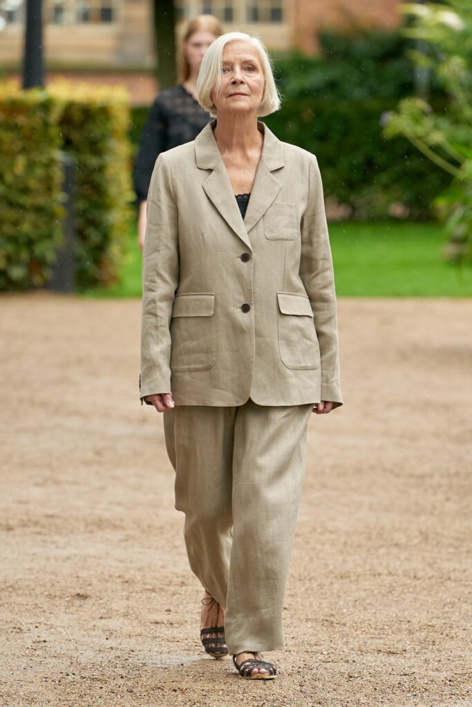 A relaxed beige linen suit featuring a collared long-sleeve jacket and buttoned details.