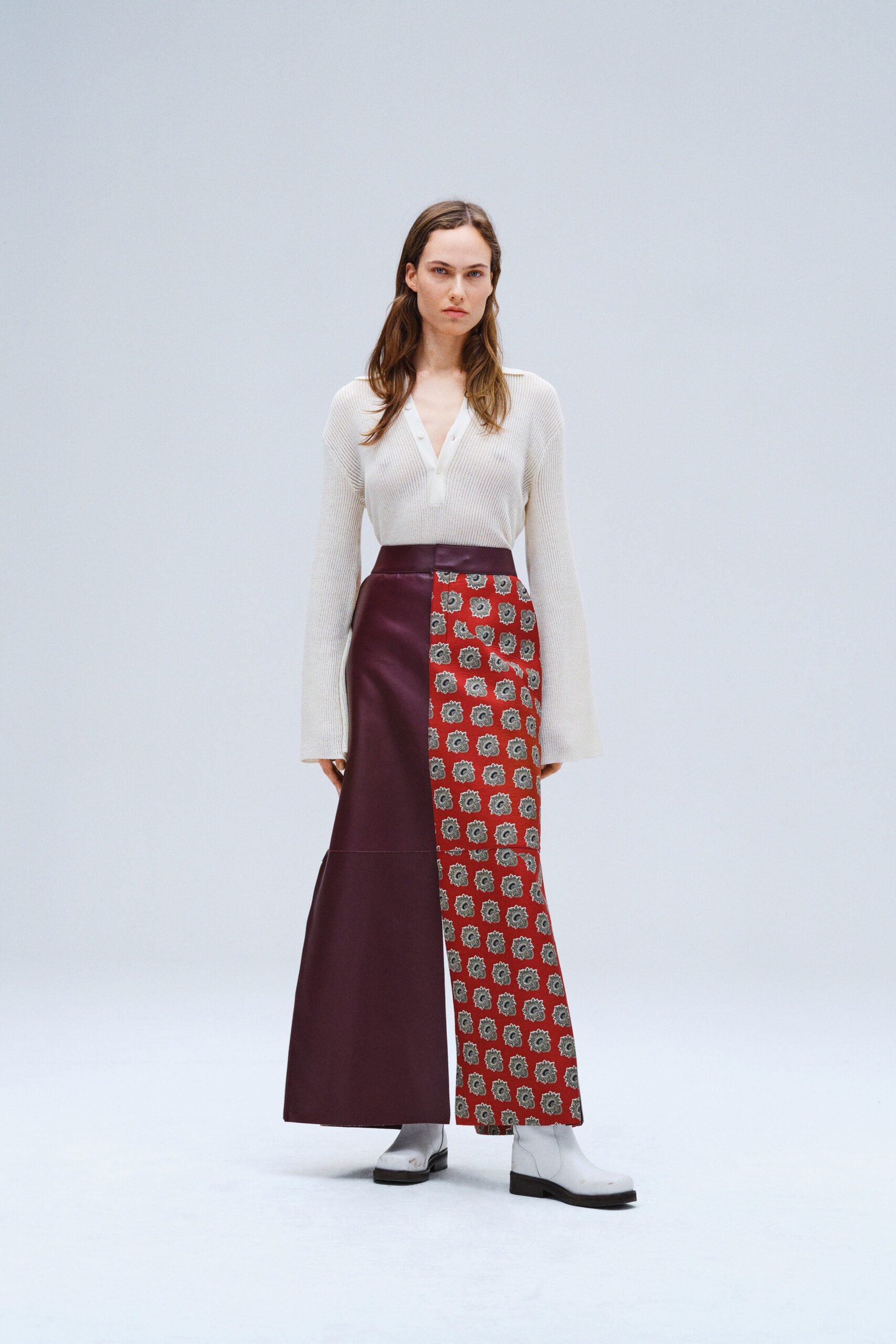 A fitted white long-sleeve top with a V-neck and asymmetric pants featuring a printed design.