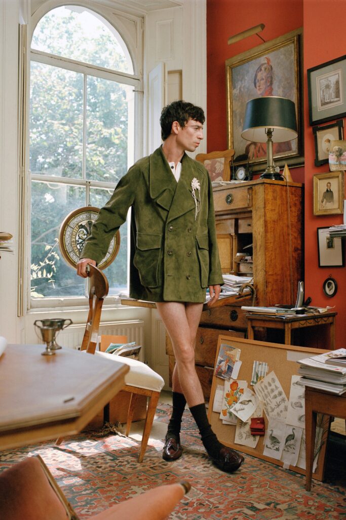 A relaxed green suede jacket paired with white shorts, featuring a collared neckline and asymmetric design.