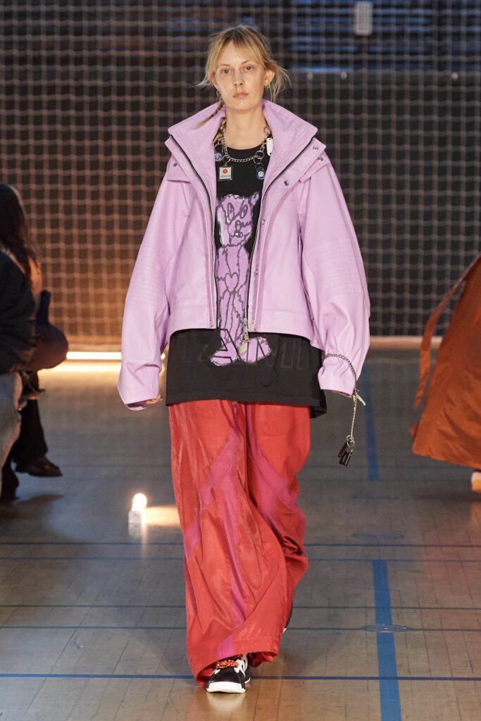 An oversized purple jacket with long sleeves paired with red pants in a layered style.