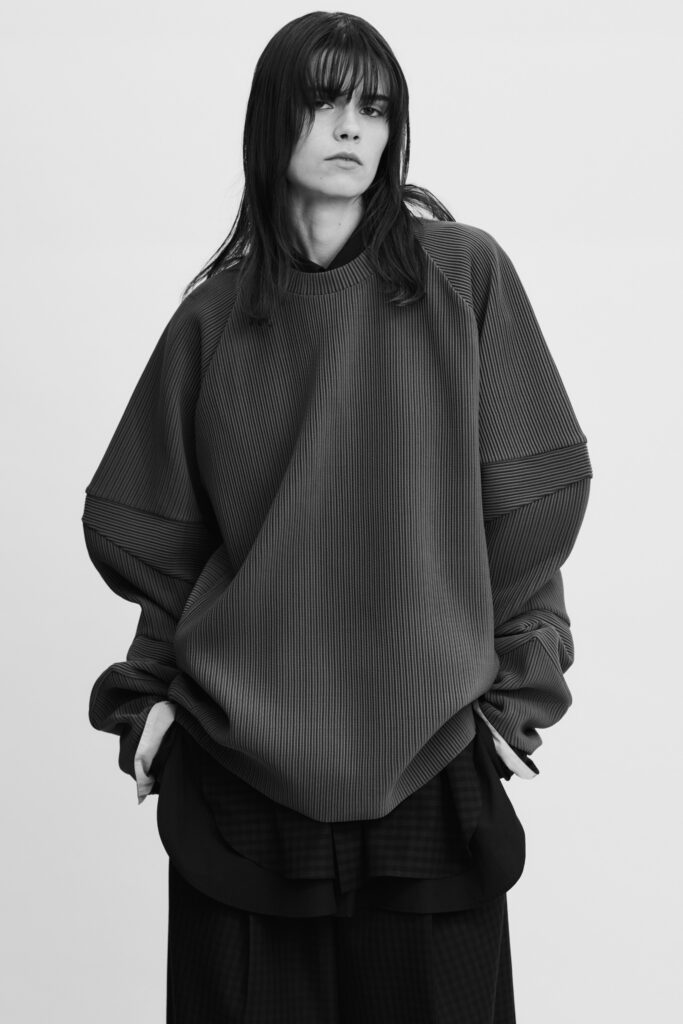 An oversized black cotton top with long sleeves paired with black pants.
