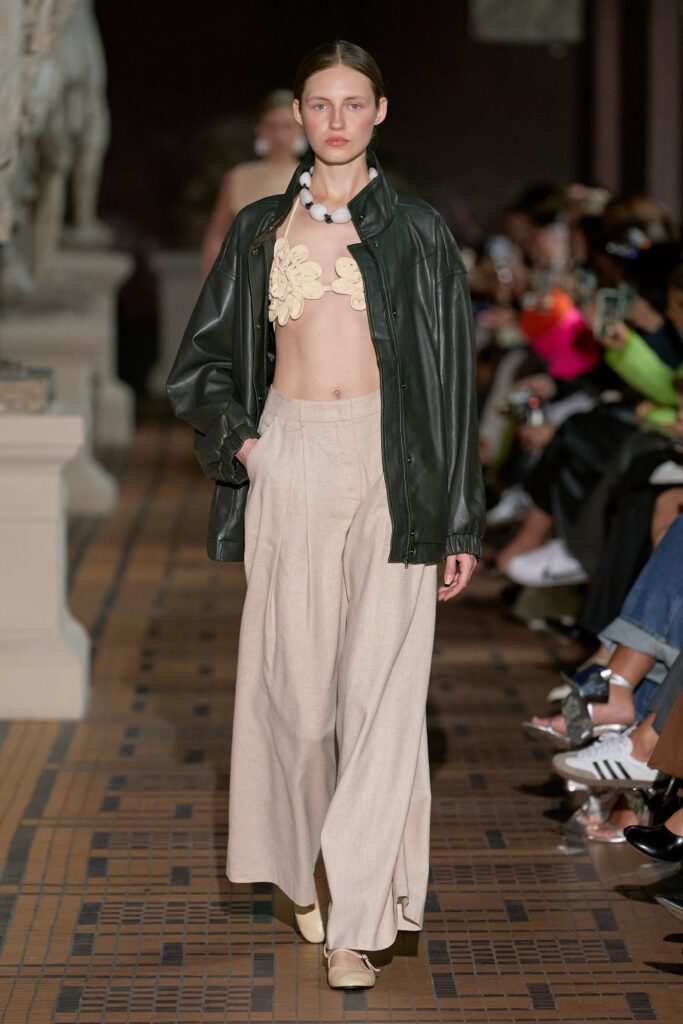 A relaxed black leather jacket paired with high-waisted beige pants featuring a wide-leg silhouette.
