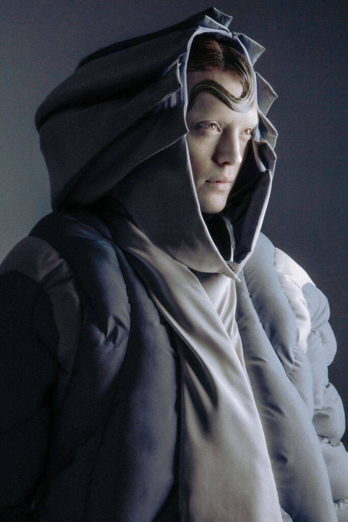 An oversized gray hooded coat made of silk with a layered design.