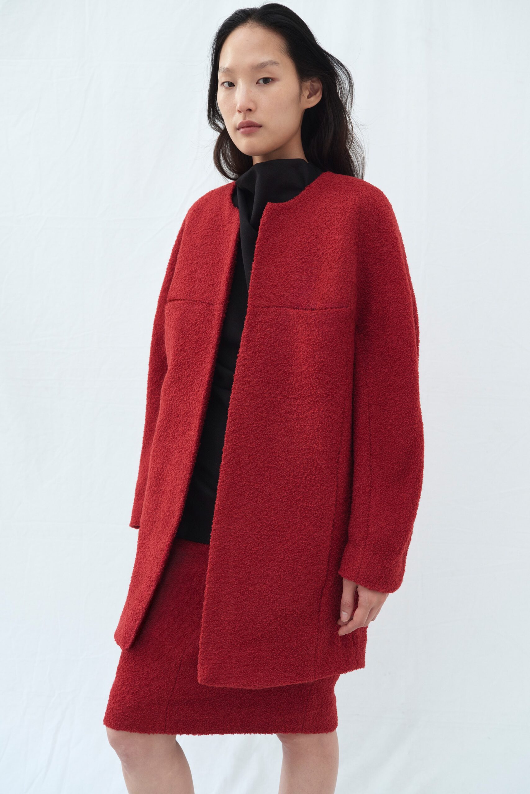 A relaxed red wool coat with long sleeves paired with a matching skirt.