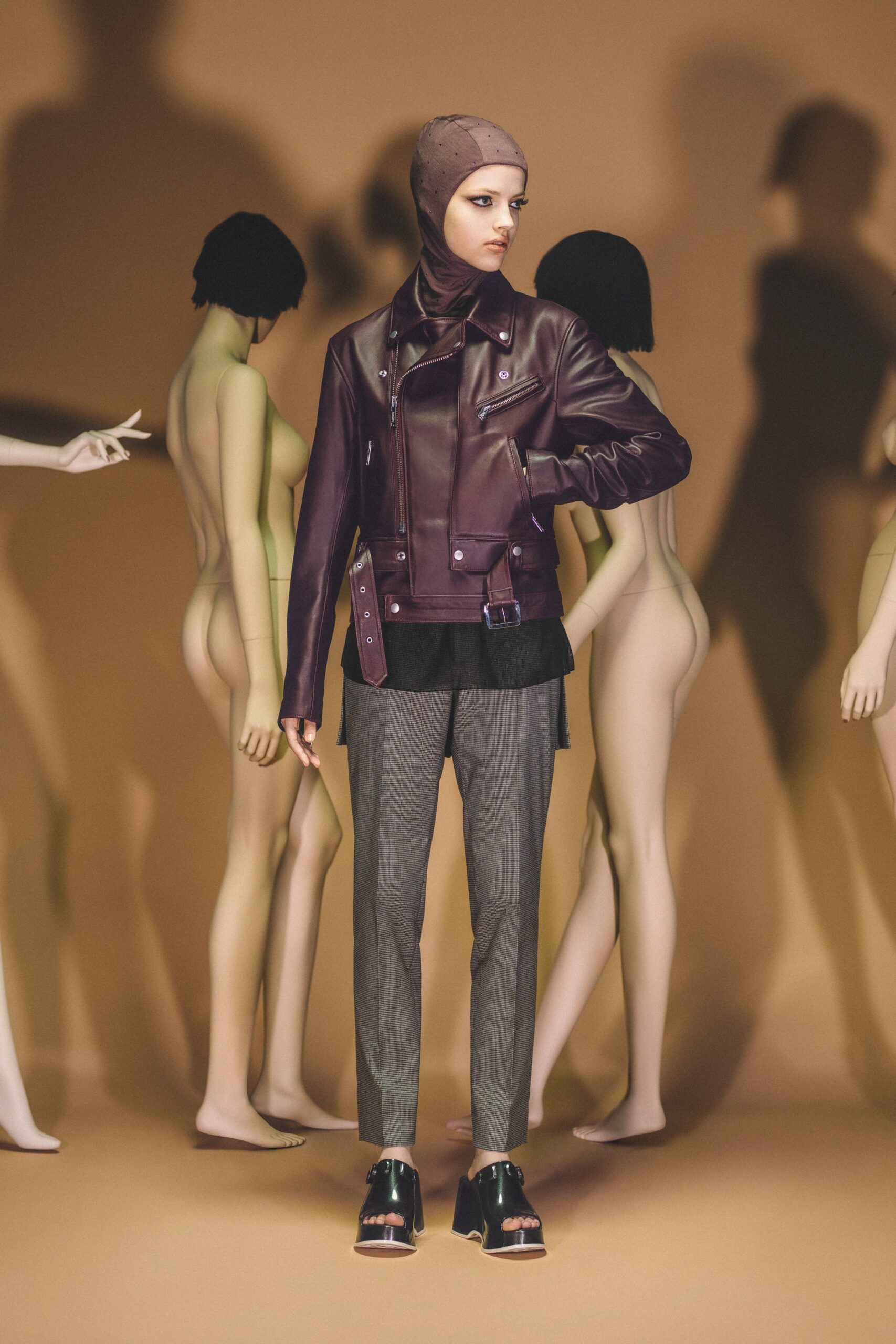 A fitted brown leather jacket with a collared neckline paired with tailored gray pants.