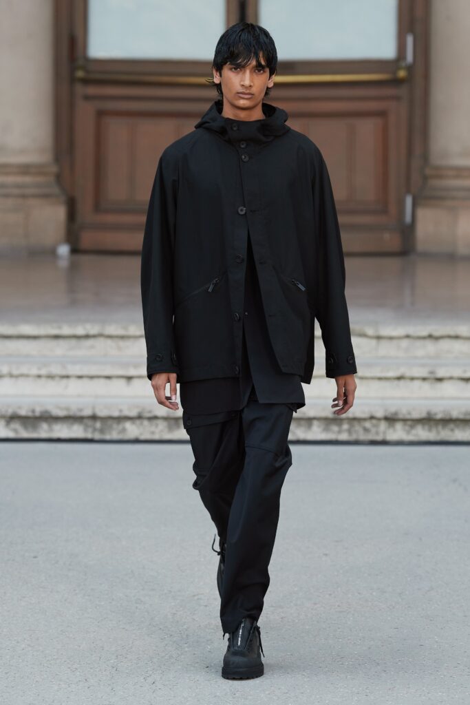 A relaxed black cotton jacket with a hood and matching pants featuring zippered details.
