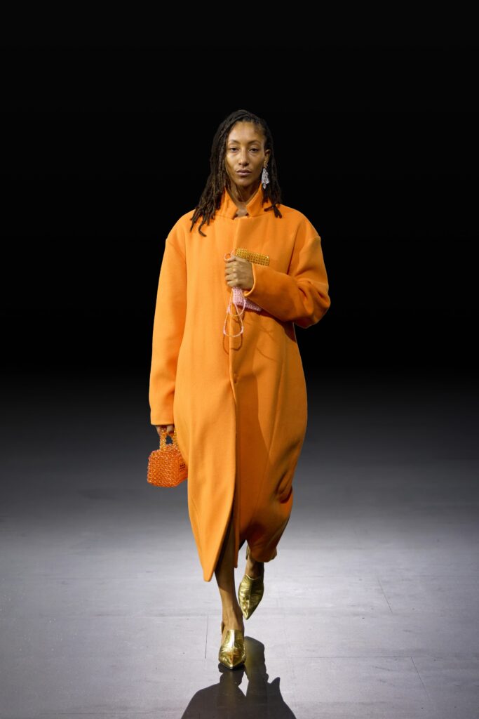 An oversized orange wool coat with long sleeves and a relaxed fit.