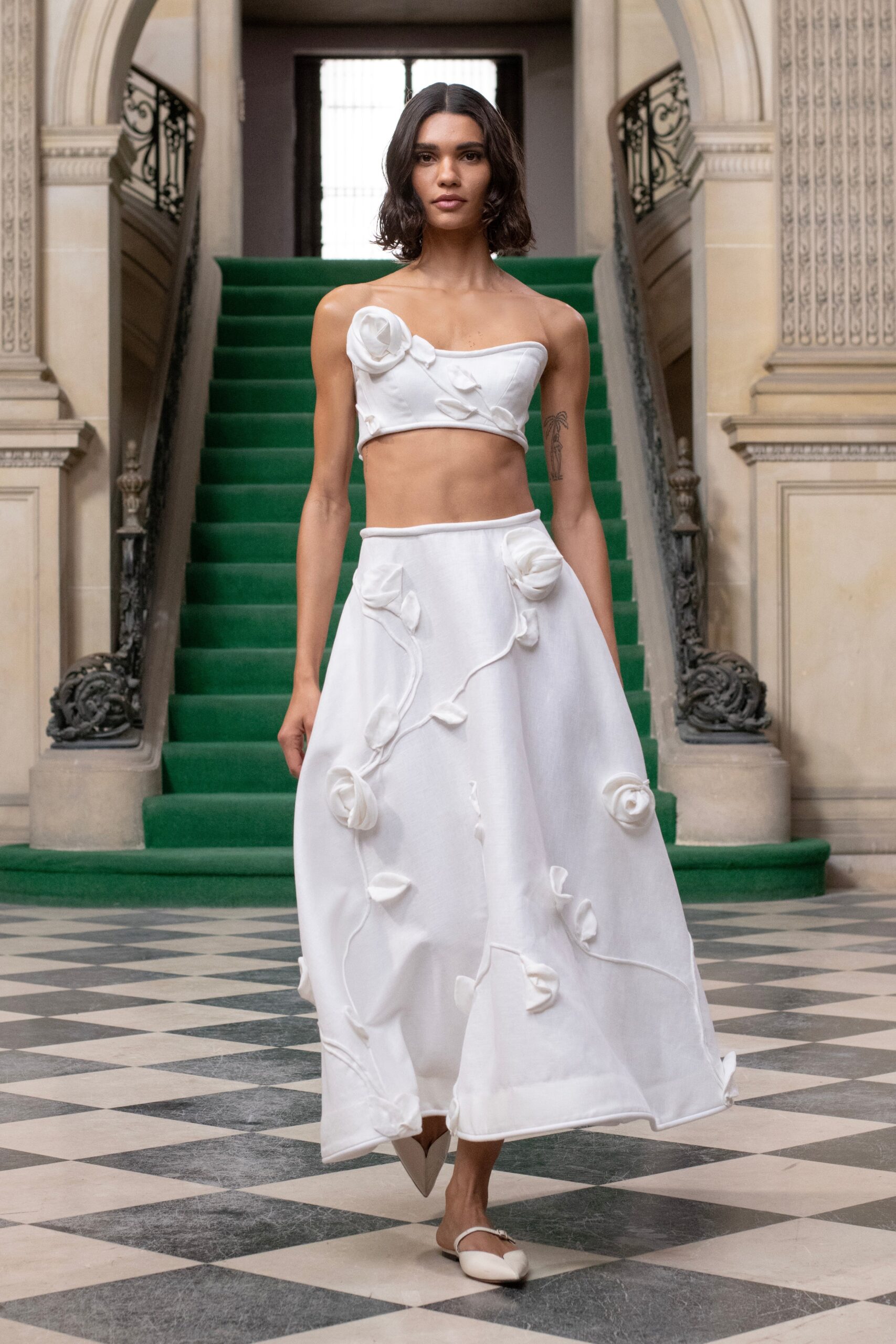A fitted white crop-top and high-waisted skirt with embroidered floral details.