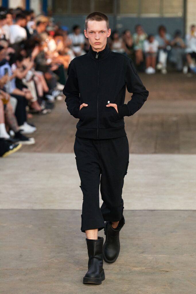 A relaxed black cotton jacket with long sleeves and matching pants featuring a zippered detail.