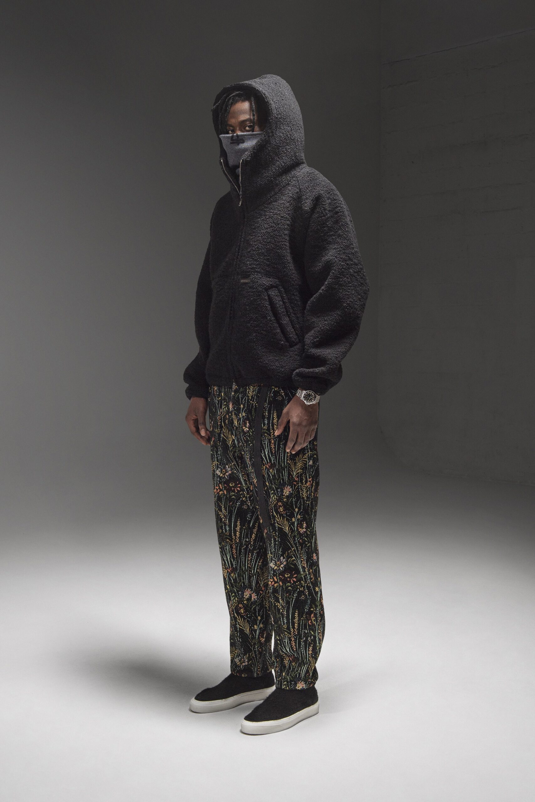A relaxed black hoodie paired with multicolored printed pants for a stylish streetwear look.