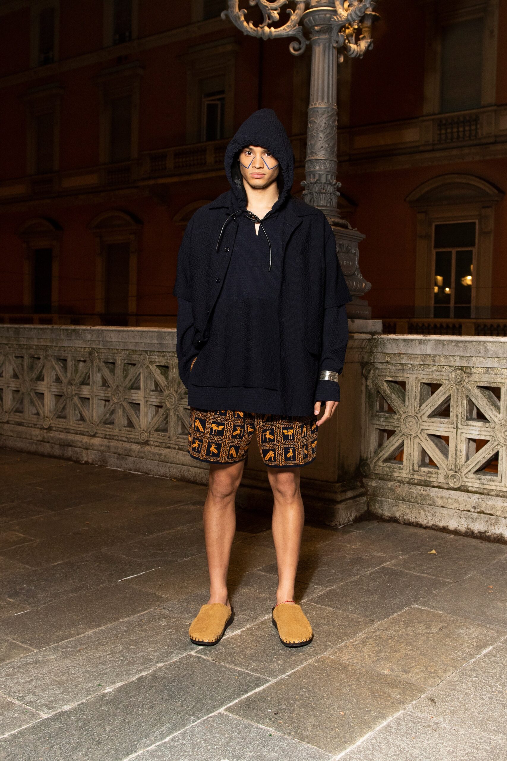 A relaxed black hoodie paired with printed shorts and brown footwear for a casual look.
