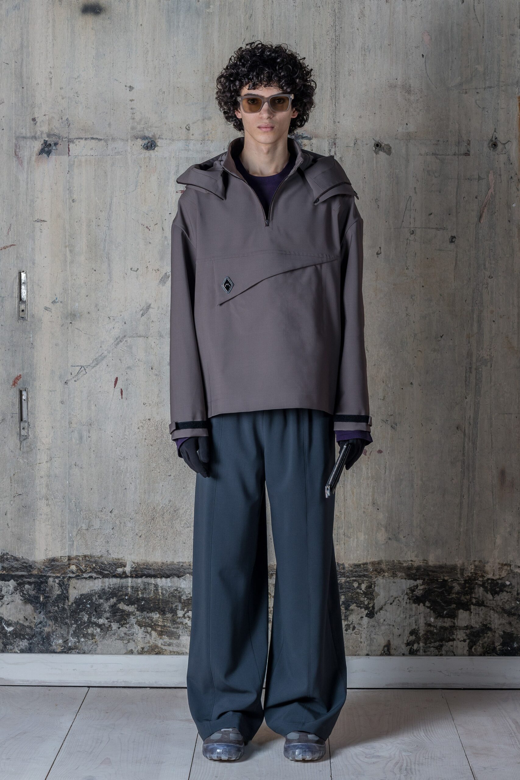 A relaxed gray jacket with an asymmetric design paired with loose-fitting pants.