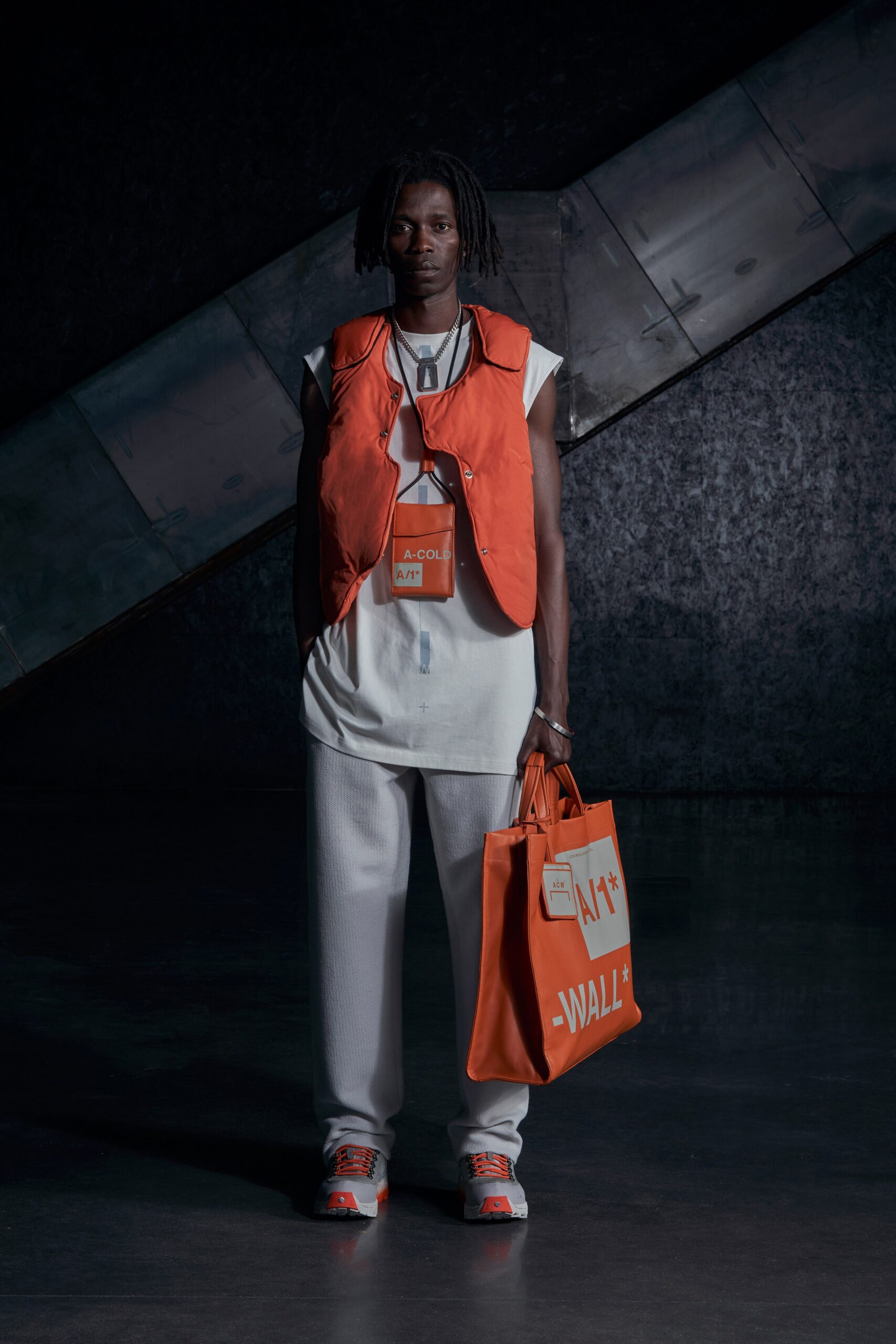 A relaxed fit orange vest layered over a white t-shirt, showcasing a modern streetwear style.