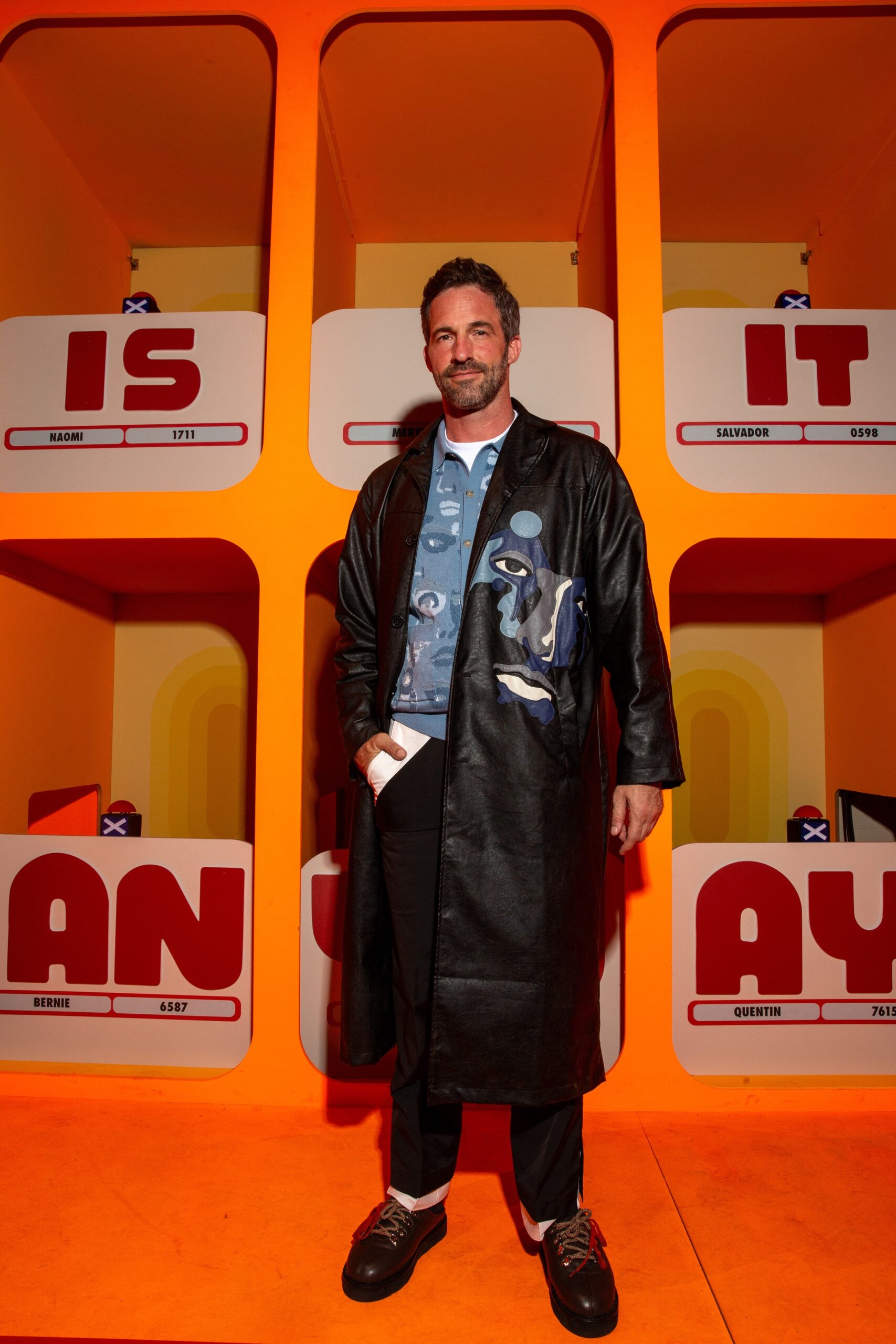 A relaxed black leather coat with long sleeves and a collared design, featuring buttoned details.