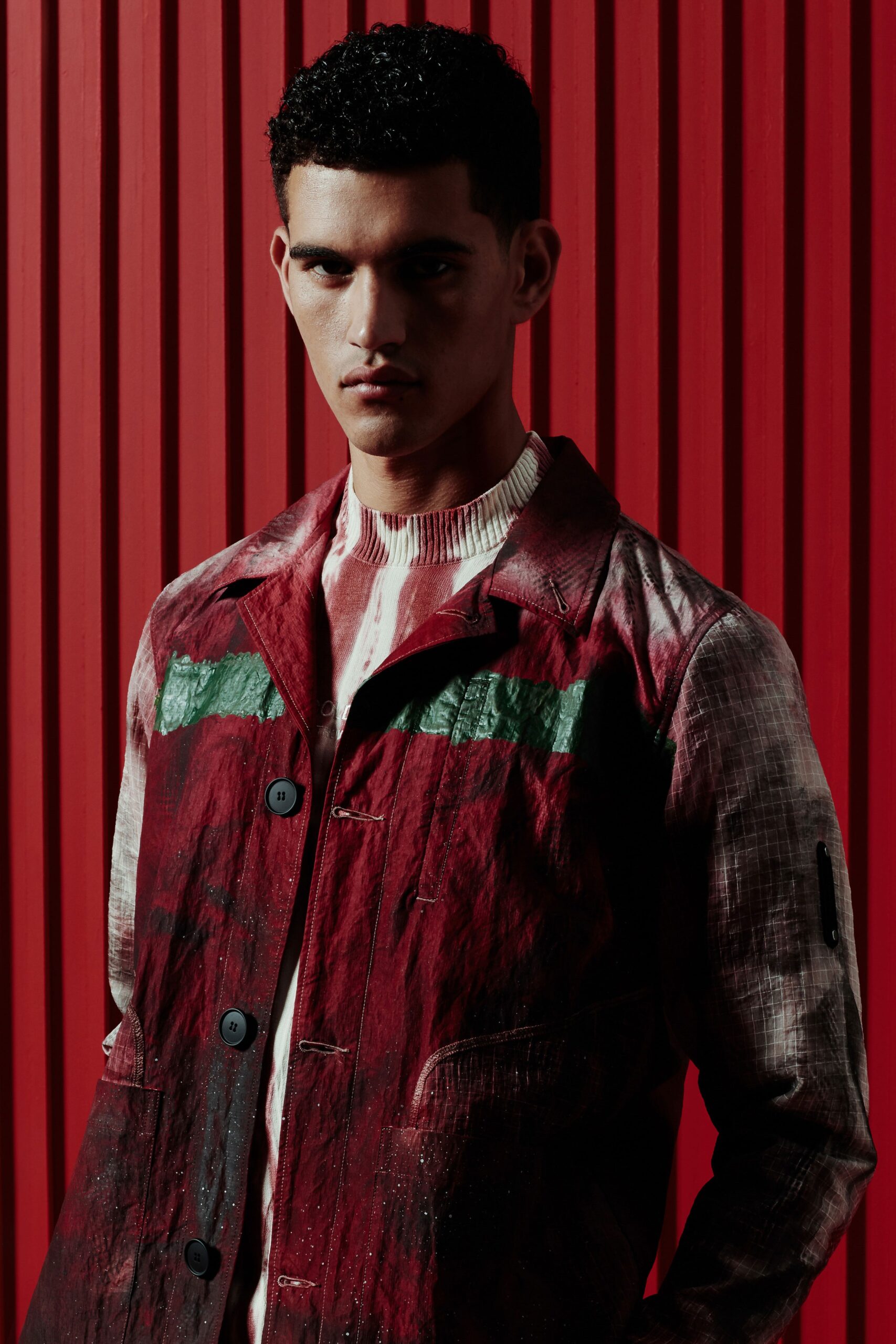 A fitted red cotton jacket with long sleeves, a collared neck, and printed details.