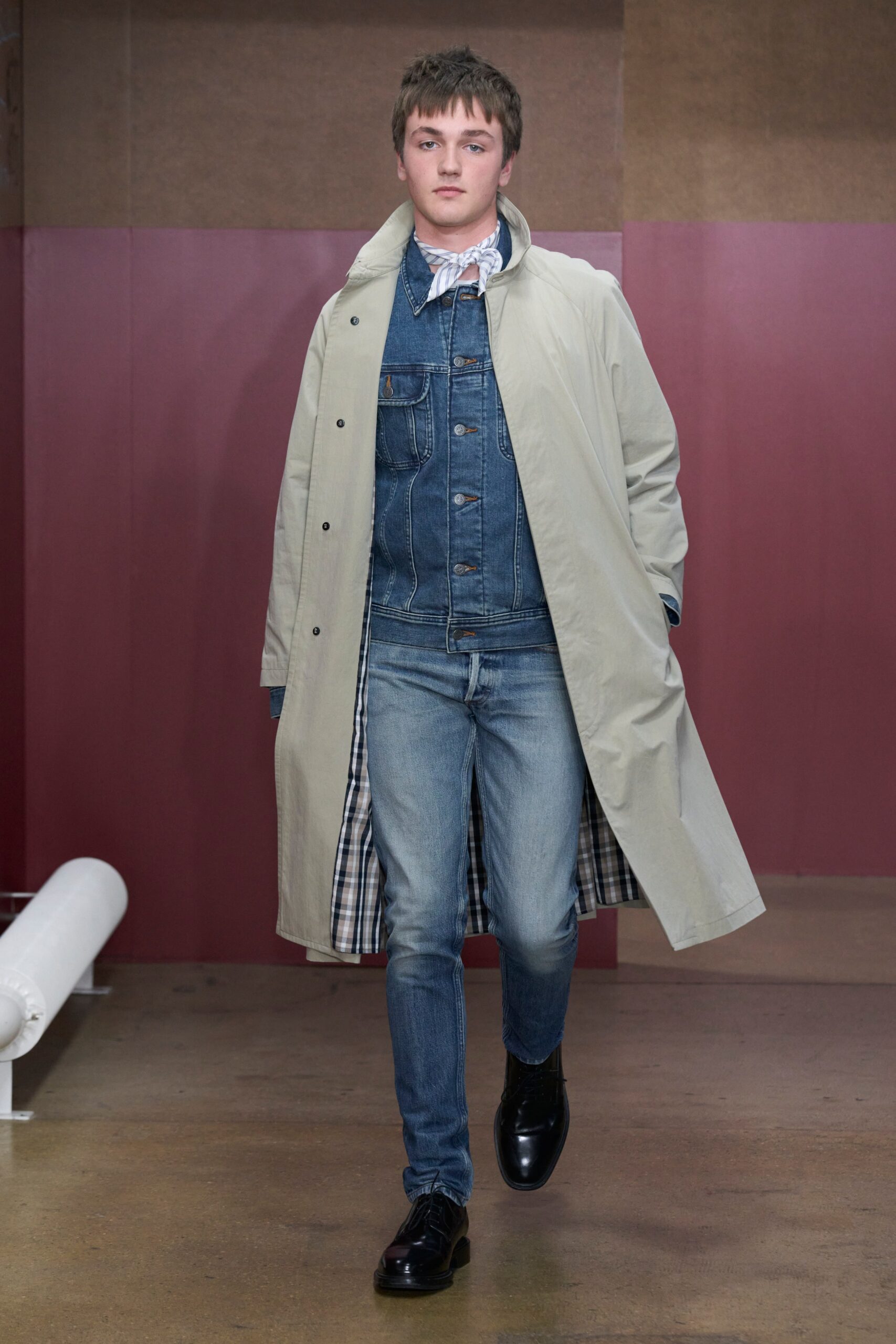 A relaxed beige coat layered over a blue denim jacket with long sleeves and a collared design.