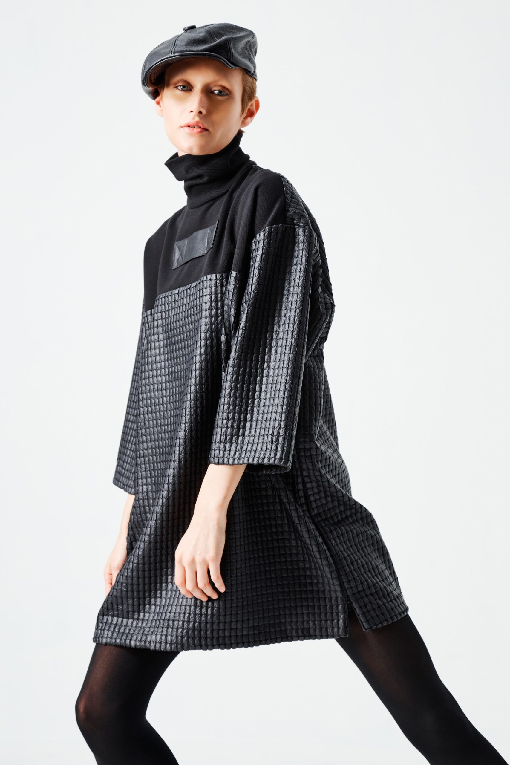 This relaxed long-sleeve dress showcases a unique textured surface that adds depth and interest. The high-neck design complements the asymmetric silhouette, creating a modern and avant-garde aesthetic.