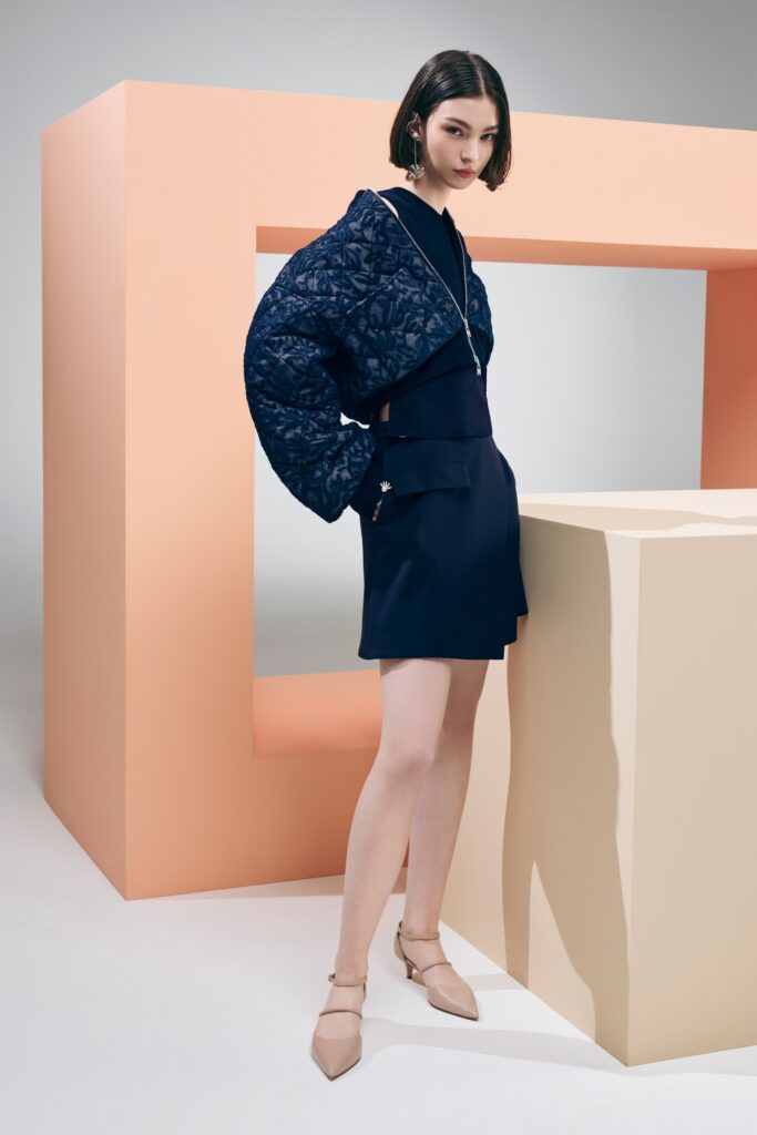 A fitted navy dress paired with a stylish long-sleeve jacket featuring an asymmetric design.
