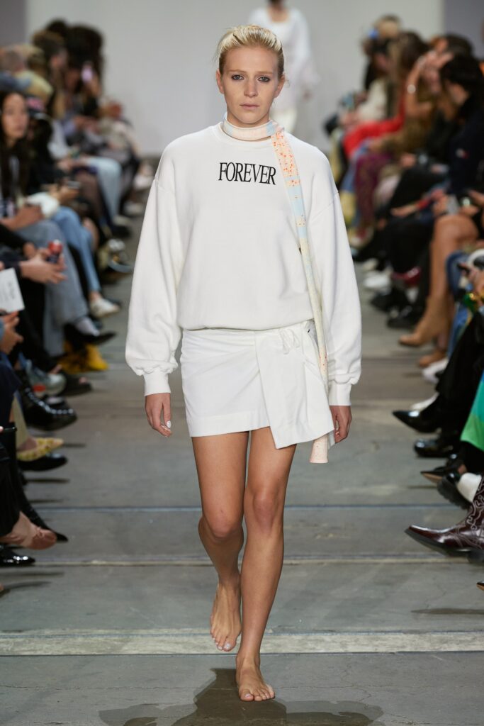A relaxed white sweater with long sleeves paired with an asymmetric white skirt.
