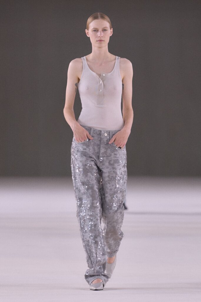 A fitted white sleeveless top paired with gray sequined straight-leg pants.