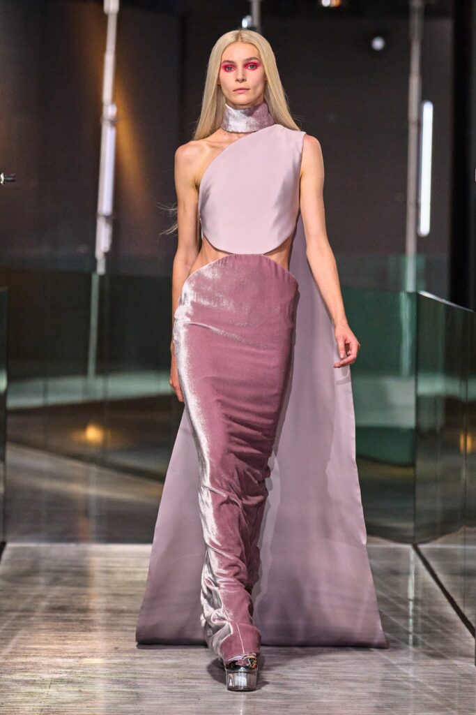 A fitted pink silk dress with a high neckline and asymmetric design.