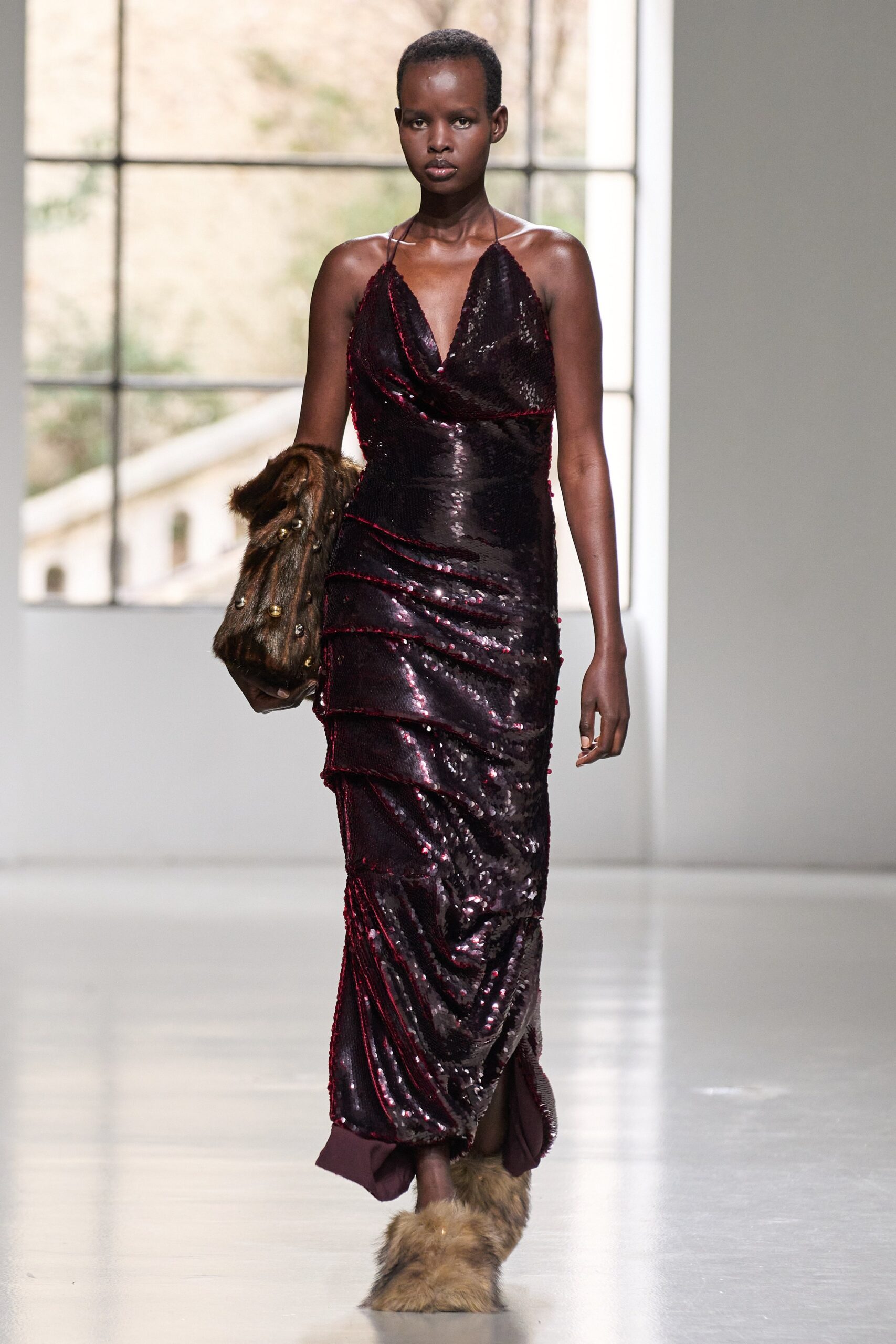 A fitted burgundy sequin dress with a sleeveless design and V-neckline, featuring a draped silhouette.