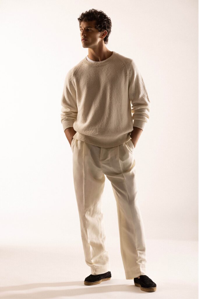 A relaxed white long-sleeve sweater paired with pleated pants for a stylish look.