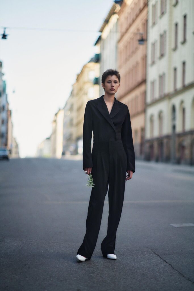 A fitted black cotton jacket with long sleeves and collared design, paired with straight-leg pants.