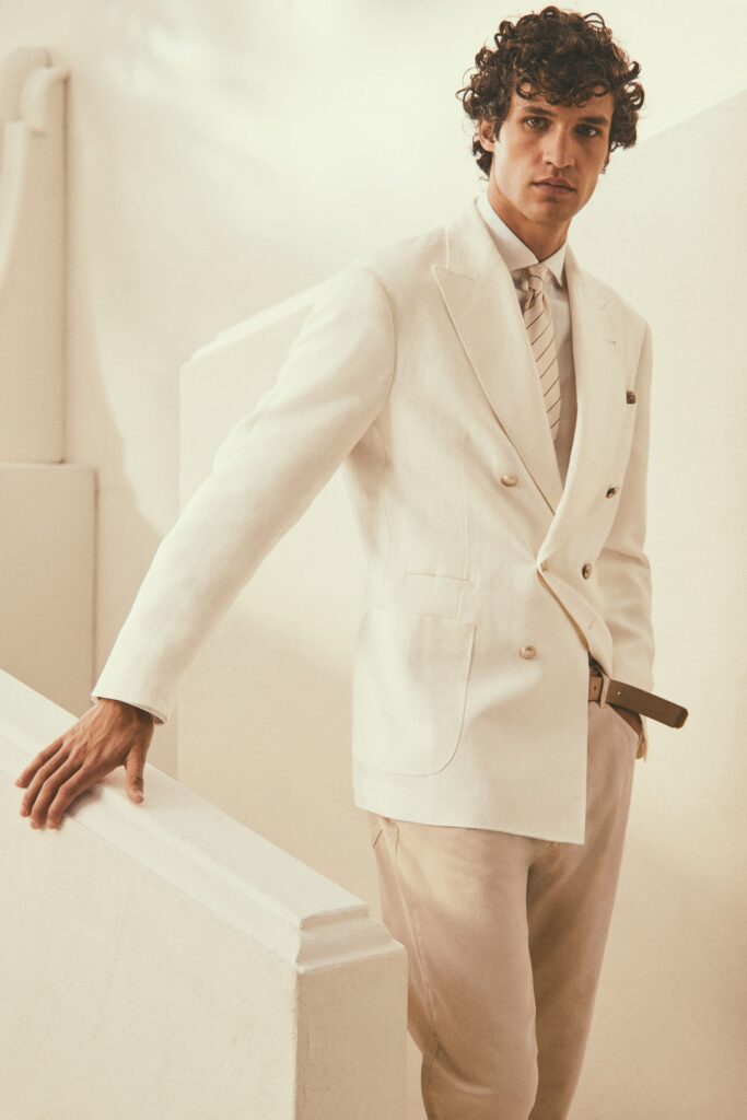 A tailored white suit with long sleeves and a collared shirt, featuring buttoned details.