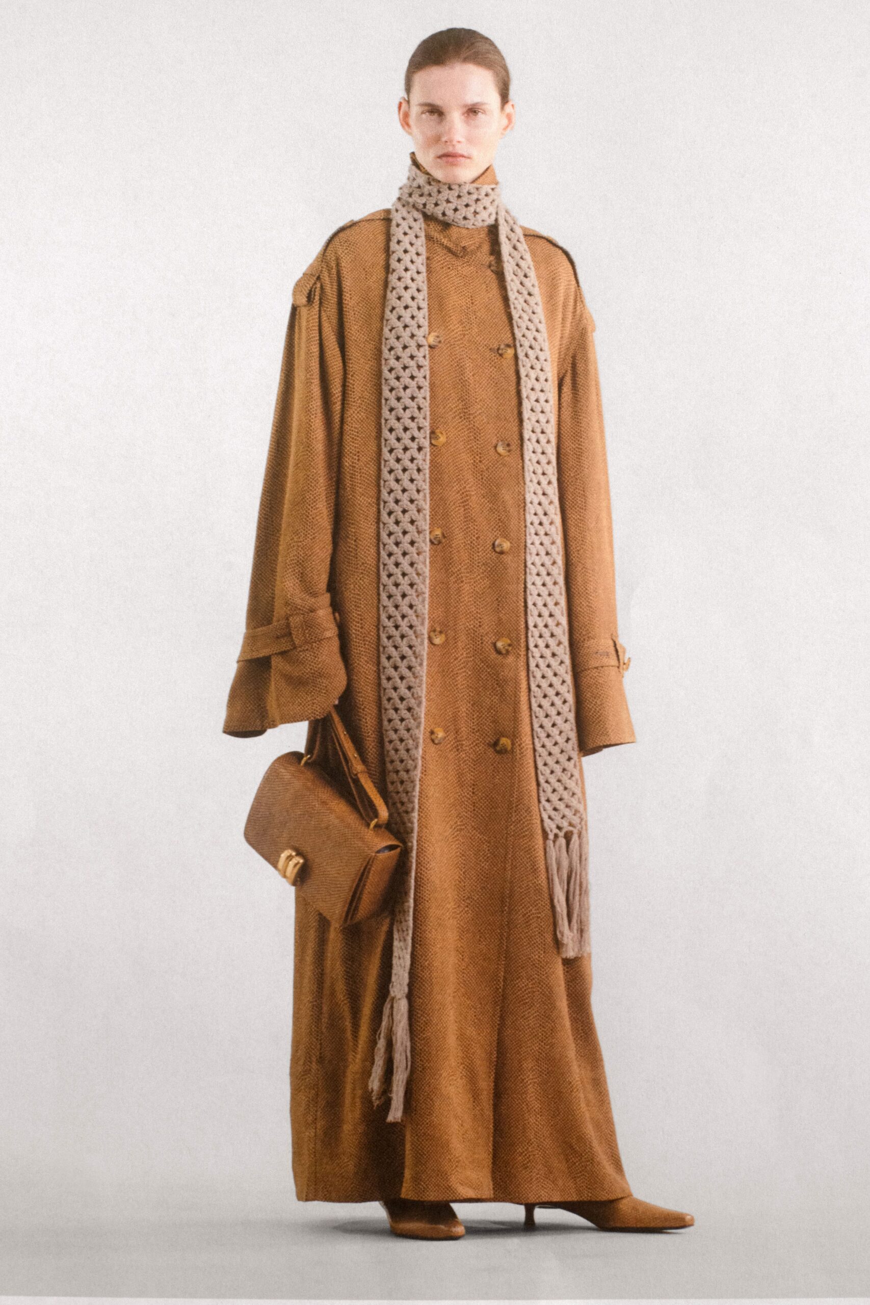 A relaxed brown wool coat with long sleeves and a collared design featuring button details.