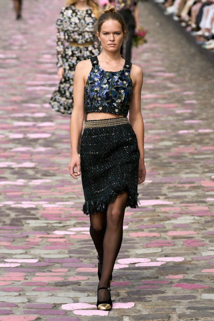 A fitted black silk sleeveless top paired with a fringed layered skirt.