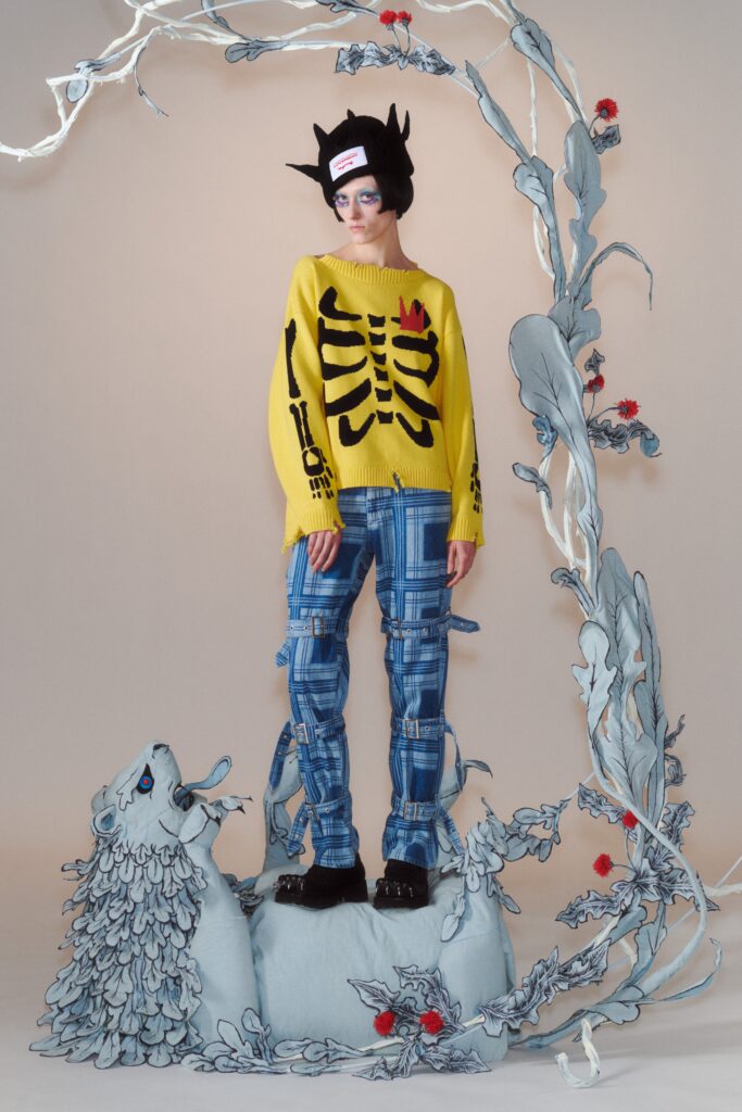 A relaxed-fit yellow printed sweater paired with straight-leg blue denim pants.