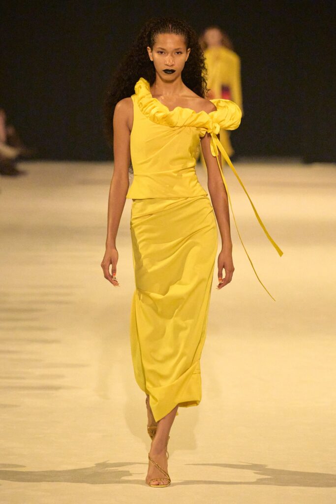A fitted yellow silk dress with a sleeveless design and ruffled asymmetric detail.