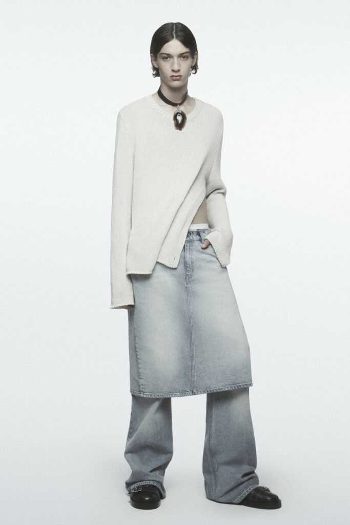 A relaxed white long-sleeve sweater paired with a blue asymmetric skirt and wide-leg jeans.
