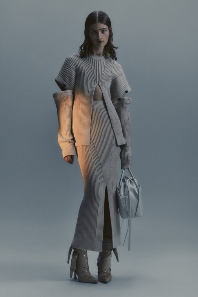 A fitted beige knit dress with long sleeves and a stylish cutout detail.