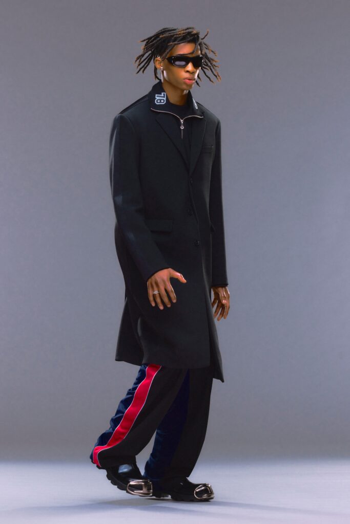 A relaxed black coat paired with blue striped pants featuring a long-sleeve and collared design.
