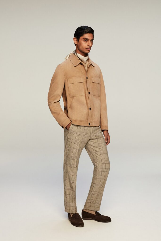 A fitted beige suede jacket paired with checked pants for a stylish look.
