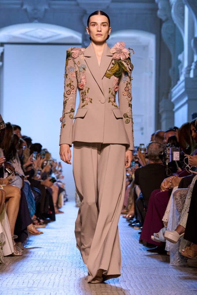 A tailored beige silk suit with long sleeves and intricate embroidery details.