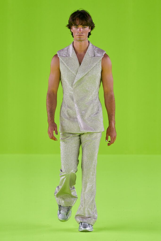 A fitted silver metallic suit with a sleeveless design and asymmetric details.