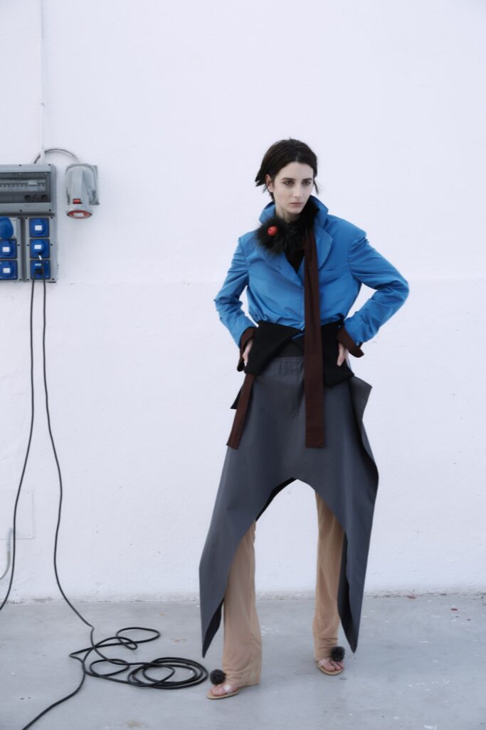 A relaxed blue jacket with a collared neckline paired with asymmetric wide-leg gray pants.