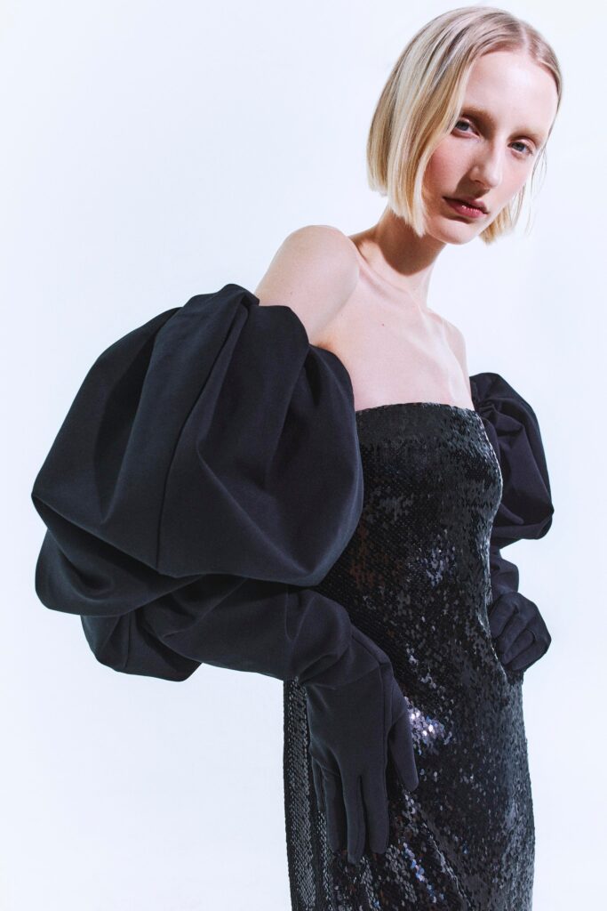 A fitted black sequin dress with an off-shoulder design and pencil silhouette.