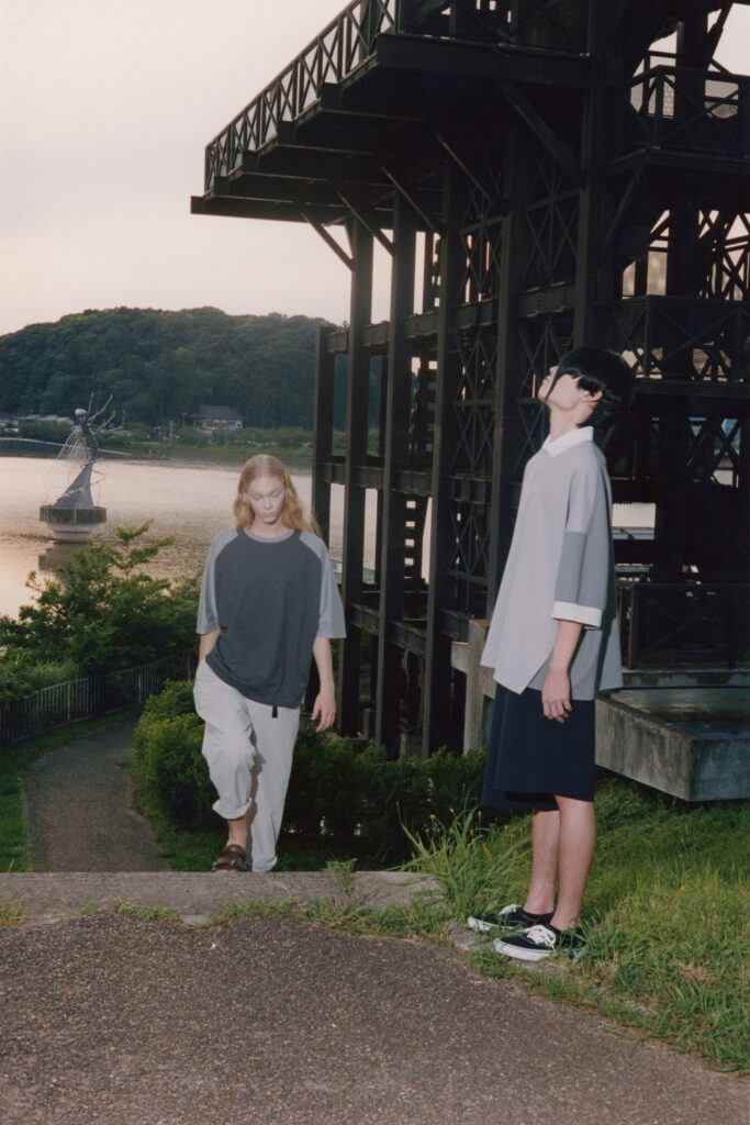 A relaxed gray cotton top with short sleeves and asymmetric design paired with white pants.