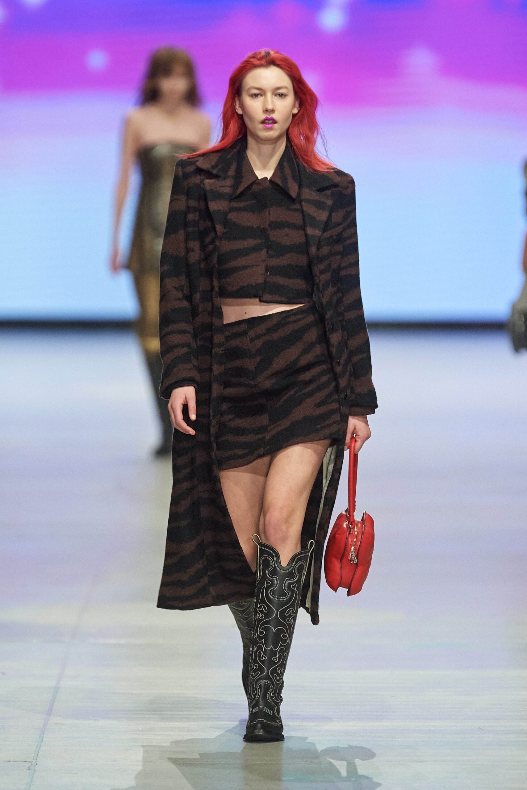 A fitted black and brown leather coat paired with a matching skirt featuring an asymmetric design and slit.
